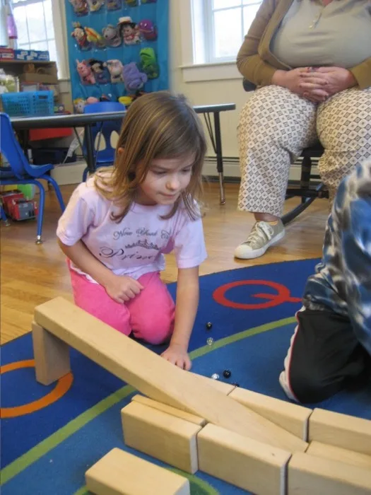 Child concentrating on Montessori marble run activity