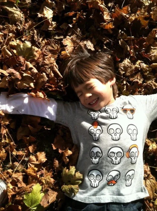 Child experiencing pure joy playing in autumn leaves